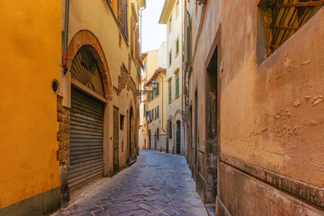 Old narrow street with rustic buildings and cobblestone pavement in Florence city, Tuscany, Italy. Firenze old town. Italian architecture
