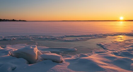 A snow-covered lake reflects the warm hues of a sunrise, breaking ice in the foreground, with distant shore
