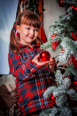 Child holding a beautiful ball on a decorated Christmas tree. Preparing for winter holidays. Decorating a Christmas tree with glass toys. Merry Christmas and happy new year!	