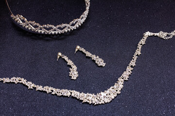 necklaces, earrings and a tiara on a black background