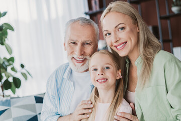 Obraz premium Warm family moment with grandma mom and daughter smiling together at home in a cozy living room with plants and shelves