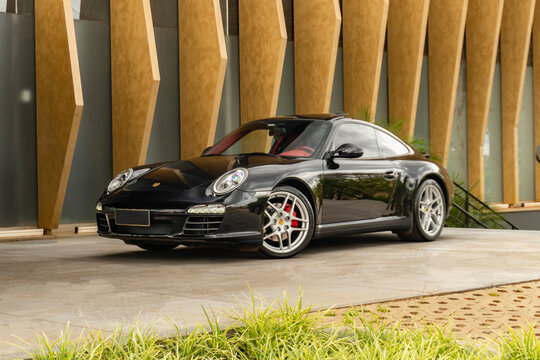 Black Porsche 911 Carrera 4S parked near modern building, luxury sportscar
