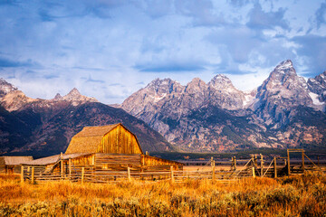 The iconic antique T.A. Moulton barn in Grand Teton National Park at Sunrise with Grand Teton and the snowcapped mountains of the Teton Range behind the field