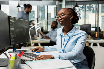 Obraz premium Prop firm office portfolio manager reviews asset performance and adjusts holdings for optimal growth. African american woman oversees diversified investment portfolios to maximize returns for clients