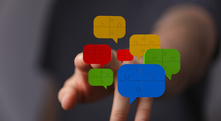 Abstract business concept of teamwork and interaction through puzzle piece speech bubbles floating near a hand. Represents communication, connec