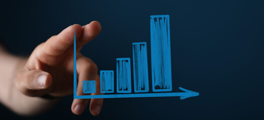 Image of a hand interacting with a bar graph illustrating upward trend, growth, and progress.