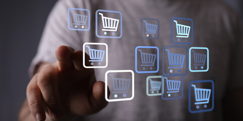 Close-up of a hand pointing at shopping cart icons, representing online shopping, ecommerce, buying, and digital transactions in modern technolo