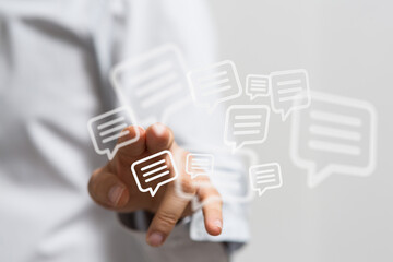 Person's hand touching speech bubble icons representing digital communication, messaging, and online interaction. Social media concept and techn