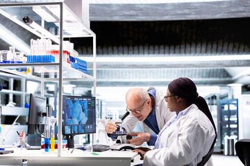 Multiethnic chemists doing a microscopy experiment in research lab. Investigation of specimen tray...