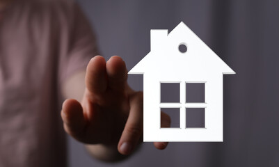 A hand reaching out to a house icon, symbolizing home ownership, real estate, or property...