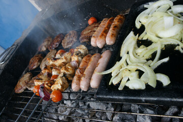 meat cooking in the garden on a barbecue, tasty summer food outdoors 