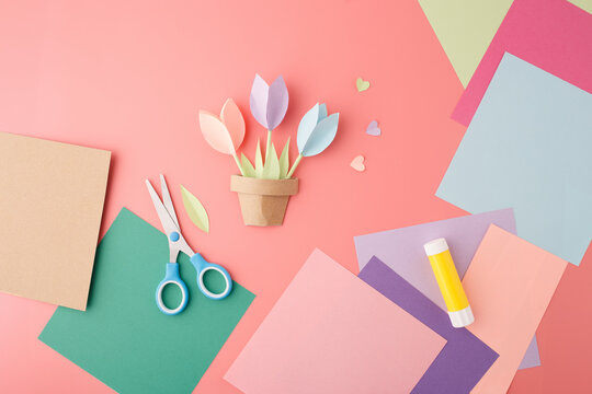 Color paper flower pot craft with glue and scissors on pink background, useful for educational content, arts marketing, early childhood branding and creative DIY tutorials,