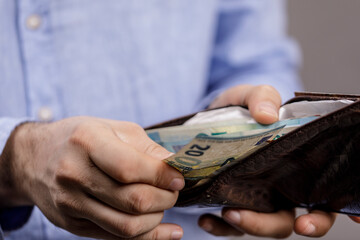 A person holding a wallet and taking out cash, depicting financial concept. Suitable for business, wealth, savings and money related concepts