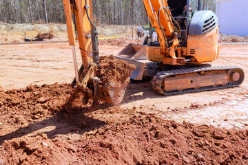 Excavator actively digs moves earth at busy construction site industrial setting machinery in...
