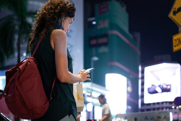 Woman checking phone in urban city at night