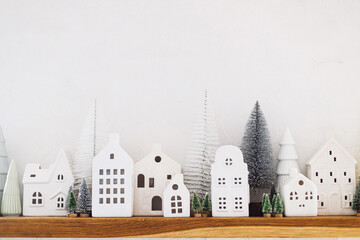 Merry Christmas! Stylish little ceramic houses and christmas trees on white background. Atmospheric...