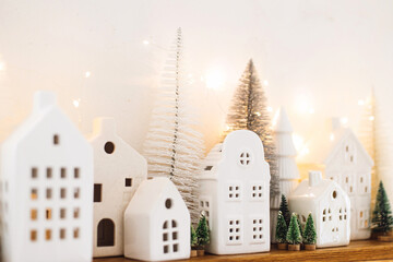 Merry Christmas! Stylish little ceramic houses and christmas trees with golden lights on white...
