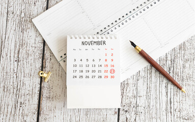 Wooden calendar organizer with date november 23 and decorative plant on table.