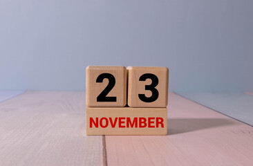 Wooden calendar organizer with date november 23 and decorative plant on table.