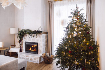 Merry Christmas! Stylish burning decorated fireplace with fir branches and Christmas tree with...