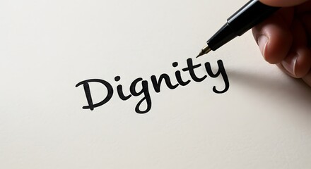 A hand writes 'Dignity' on paper, symbolizing human self-worth, personal respect, and the foundational importance of ethical values in modern society and individual conduct