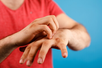 A man is scratching his hand. The image showcases a person suffering from itchy skin, potentially...