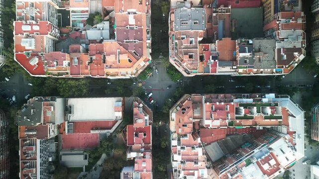 4K drone aerial view of Eixample district in Barcelona, Spain, showing iconic grid city layout, geometric blocks and tree-lined streets on a sunny day