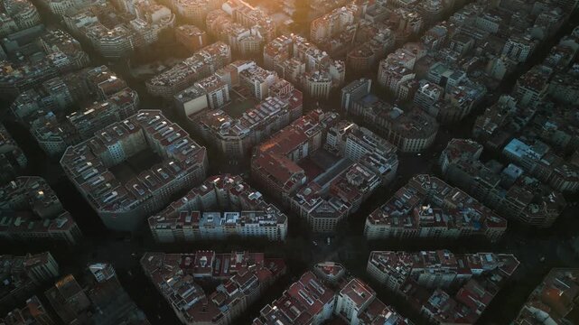 4K drone aerial view of Eixample district in Barcelona at sunset, showing iconic grid city pattern, warm evening light and Mediterranean urban landscape, Spain