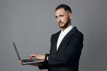 Professional businessman with a laptop demonstrates calm focus and confident stance against a solid colored background, conveying executive presence and determination.