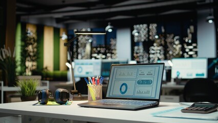 High end empty workspace features laptop with data charts for forecasting. Modern space set for corporate planning, analytics and performance indicators that drive organizational success.