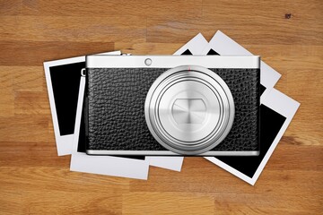 Old retro photo camera with photographs on wooden table