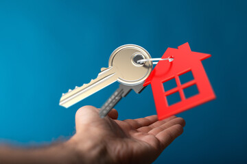 A hand holding a key with a house shaped tag, symbolizing home ownership, buying a house or real estate investment. Perfect for real estate, mor © vegefox.com