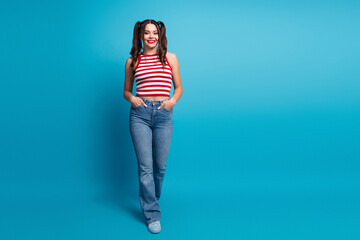 Attractive young woman in trendy casual outfit posing against vibrant blue background showcasing...