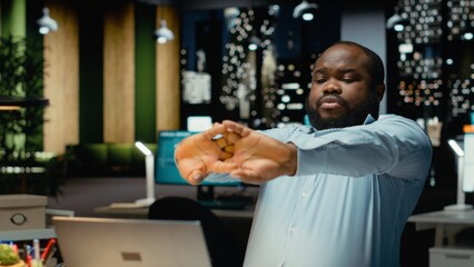 African american guy handles daily tasks late at night with ambience music on headset, finding inspiration with focus sounds to help with concentration and productivity. Male multitasking.