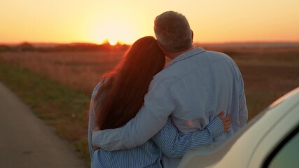 Man woman hug enjoying sunset next to car on road. Happy family. Man woman couple standing hugging enjoying car trip out of town. People travel by car, leading active lifestyle in nature on vacation