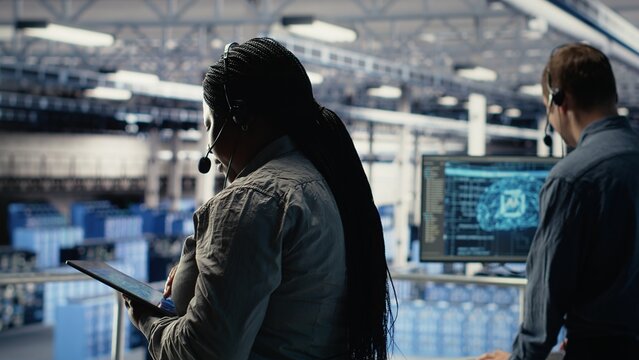 Data center colleagues using artificial intelligence to help customers resolve website hosting problems. Server room tech support coworkers help users keep internet services running smoothly, camera B