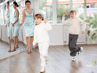 Fototapeta premium Boy and girl train to dance contemporary vigorous hip hop during classes. Female teacher conducts class for teen students during dance workout