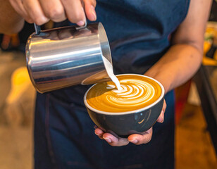 Barista Pouring Milk into Coffee Cup Creating Latte Art Swirls, Close-Up.