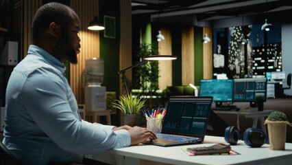 Male finance analyst reviews trading accounts and archived data for revenue reports, using digital graphs to plan resources allocation and align business targets with financial success.