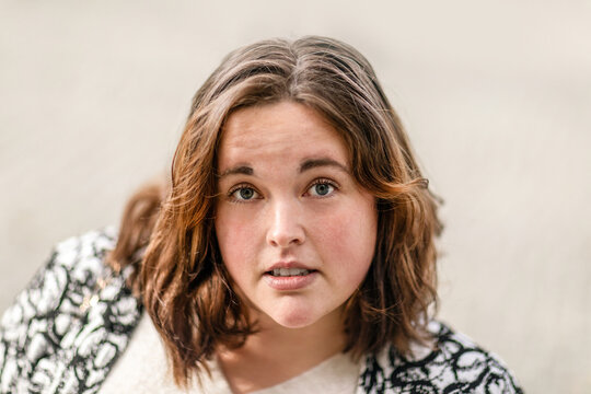 Young woman with natural look and short brown hair outdoors looking directly at camera