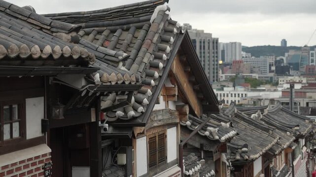 Traditional Korean hanok rooftops contrasting with the modern Seoul city skyline