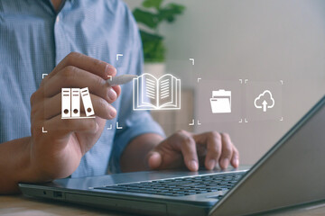 Person using a laptop and interacting with digital icons of books, folders and cloud storage, symbolizing document management, digital organization and cloud-based file storage.