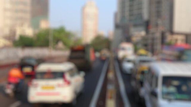 Bokeh view of road traffic near Mahalaxmi suburban railway station in Mumbai, India. Blurred background footage.