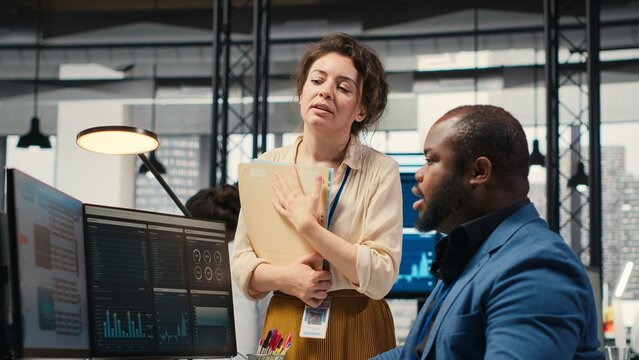 Multiethnic work team consulting each other in completing monthly reports, reviewing KPI data insights for business productivity. Collaboration between employees for success. Camera B. - Powered by Adobe