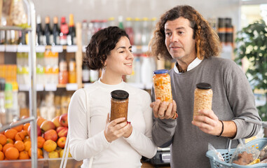 Husband and wife shopping together at the supermarket - choosing jar of beans and lentils