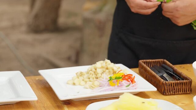 Chef garnishing peruvian ceviche with fresh herbs