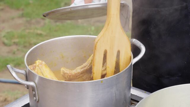 Chef stirring peruvian meat stew cooking outdoors