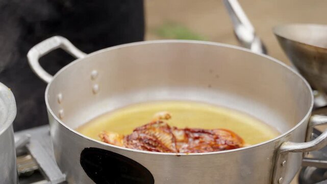 Chef deep frying a whole guinea pig in hot oil