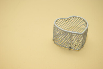 Empty heart-shaped metal basket on beige surface