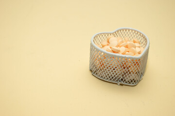 Heart-shaped metal basket filled with pills